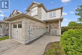 Guelph (Pineridge/Westminster Woods) townhouse for rent - A house with a white garage door and a stone wall.