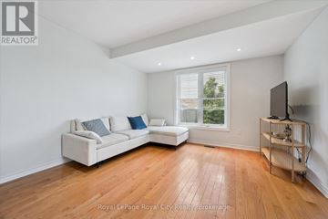 Guelph (Pineridge/Westminster Woods) townhouse for rent - A living room with a white couch and a television on a wooden stand.