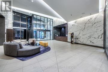 Toronto (Waterfront Communities) condo for rent - A spacious living room with a grey sofa and a yellow ottoman.