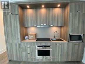 Toronto (Waterfront Communities) condo for rent - A modern kitchen with wooden cabinets and a box labeled "good bit" on the counter.
