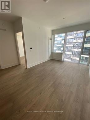 Toronto (Waterfront Communities) condo for rent - A spacious room with wooden flooring and a large window.