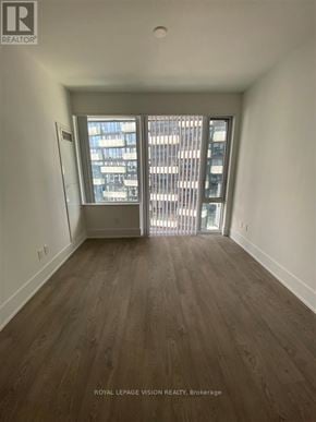 Toronto (Waterfront Communities) condo for rent - A room with wooden flooring and a window overlooking a cityscape.