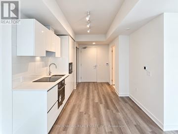 Toronto (University) condo for rent - A modern kitchen with white cabinets and a wooden floor.