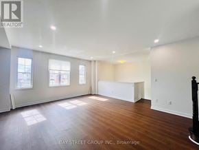 New Tecumseth apartment for rent - A spacious room with wooden floors and white walls, with a large window on the left side.