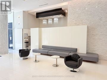 Toronto (Mimico) condo for rent - A modern living room with a grey sofa and black armchair.