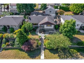 Burnaby apartment for rent - A large house with a grey roof is surrounded by a well-maintained lawn and trees.