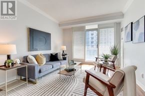 Toronto (Mimico) condo for rent - A living room with a grey couch, a wooden chair, and a striped rug.