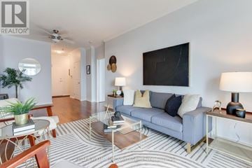Toronto (Mimico) condo for rent - A living room with a grey couch, a coffee table, and a television mounted on the wall.