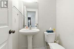 Brantford townhouse for rent - A white bathroom with a sink, mirror, toilet and toilet paper.
