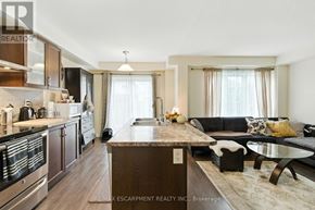 Brantford townhouse for rent - A modern kitchen with a wooden island and a dining area with a black couch.