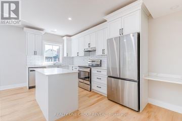 Clarington (Bowmanville) triplex for rent - A modern kitchen with white cabinets and stainless steel appliances.