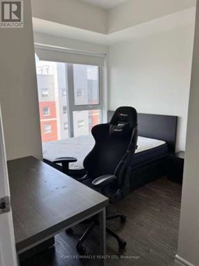 Waterloo condo for rent - A black gaming chair is in a white room with a desk and a window.