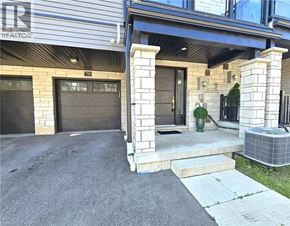 Cambridge townhouse for rent - A house with a garage and a porch with a potted plant on it.