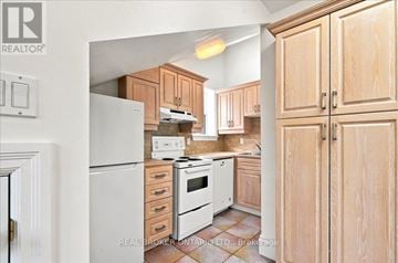Toronto (Yonge-St. Clair) fourplex for rent - A kitchen with wooden cabinets and a white refrigerator.