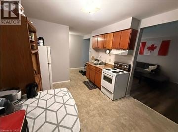 Kitchener condo for rent - A kitchen with a stove, refrigerator, and a table with a white and grey tablecloth.