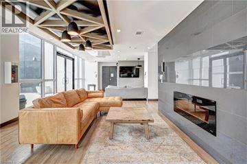 Kitchener condo for rent - A modern living room with a tan sofa and a fireplace.