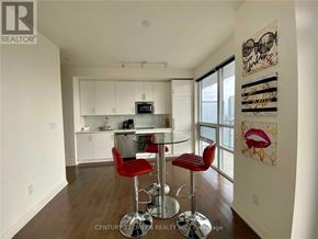 Toronto (Moss Park) condo for rent - A modern kitchen with white cabinets and a glass table.