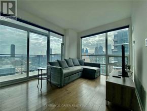 Toronto (Moss Park) condo for rent - A living room with a couch and a table in front of a large window.