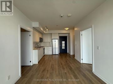 Toronto (Henry Farm) condo for rent - A spacious kitchen with white cabinets and a dark door.