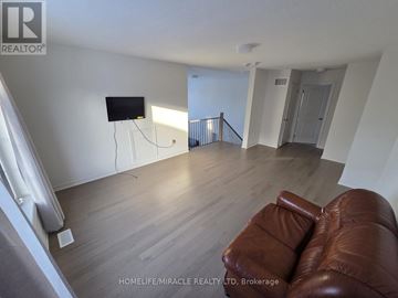 Adjala-Tosorontio (Colgan) townhouse for rent - A living room with a brown leather couch and a flat screen TV mounted on the wall.