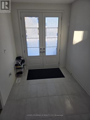 Adjala-Tosorontio (Colgan) townhouse for rent - A white door with a glass window is in a room with a black mat on the floor.