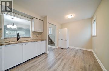 Oakville townhouse for rent - A well-lit kitchen with white cabinets and a wooden floor.