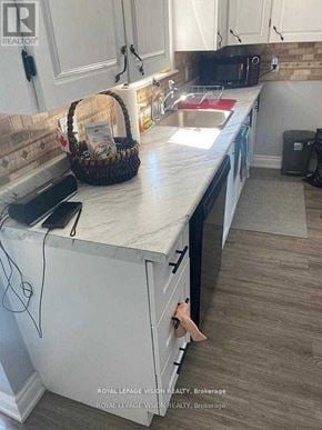 Tweed (Tweed (Village)) apartment for rent - A kitchen with white cabinets and a white countertop with a basket on it.