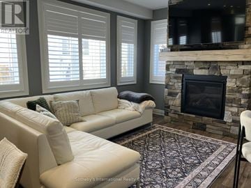 Collingwood townhouse for rent - A living room with a white couch and a stone fireplace.
