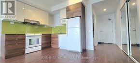 Toronto (Bayview Village) condo for rent - A kitchen with a white fridge and a white oven with a green wall.
