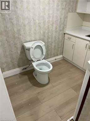Hamilton apartment for rent - A white toilet in a small bathroom with wooden flooring.