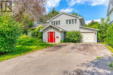 Oakville (Sw Southwest) apartment for rent - A house with a red door is surrounded by greenery and has a driveway leading to the garage.