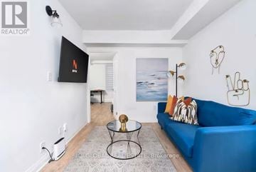 Toronto (Palmerston-Little Italy) triplex for rent - A living room with a blue couch and a flat screen TV mounted on the wall.