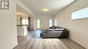 London North (North S) apartment for rent - A spacious living room with a large black sofa and wooden flooring.