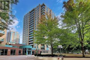 Toronto (Willowdale East) condo for rent - A tall building with a glass facade is surrounded by trees and other buildings.
