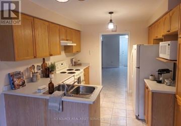 Barrie (Painswick South) apartment for rent - A kitchen with wooden cabinets and a white refrigerator.