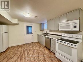 Toronto (Corso Italia-Davenport) duplex for rent - A kitchen with white appliances and wooden floors.