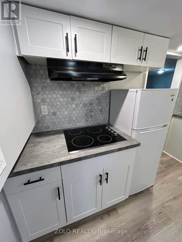 Kitchener apartment for rent - A kitchen with white cabinets and a black stove top.
