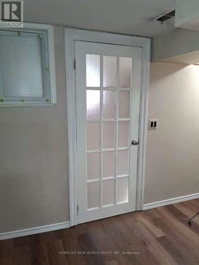 Toronto (Woburn) apartment for rent - A white door with a glass panel is in a room with wooden flooring.
