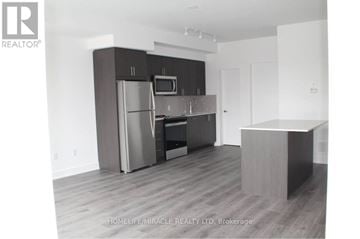 Oshawa (Windfields) townhouse for rent - A modern kitchen with a refrigerator, microwave, and oven.