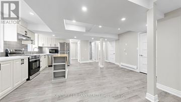 Kitchener apartment for rent - A spacious kitchen with white cabinets and a wooden floor.