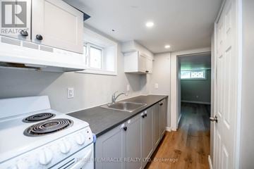 Niagara Falls (Downtown) apartment for rent - A kitchen with white cabinets and a white stove top oven.
