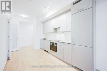 Mississauga (City Centre) condo for rent - A well-lit, spacious kitchen with white cabinets and a wooden floor.