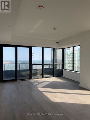 Mississauga (City Centre) condo for rent - A spacious room with large windows overlooking a cityscape.
