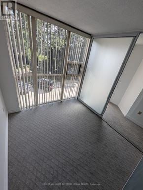 Toronto (Niagara) condo for rent - A room with a carpeted floor and a glass door leading to a balcony.