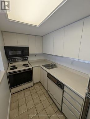 Toronto (Niagara) condo for rent - A kitchen with white cabinets and a black microwave.