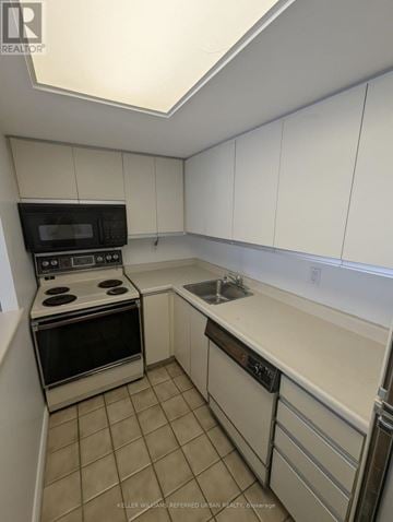 Toronto (Niagara) condo for rent - A kitchen with white cabinets and a black microwave.