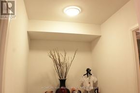 Toronto (Mimico) condo for rent - A vase with dry stems sits on a table in a room with a ceiling light.
