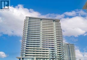 Mississauga (Central Erin Mills) condo for rent - A tall building with many windows and balconies is under a blue sky with clouds.
