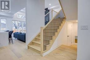 Toronto (Mimico) apartment for rent - A staircase with a black railing leads to a door in a white room.