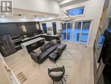 Toronto (Mimico) apartment for rent - A modern living room with a large sectional sofa and a kitchen area with a bar stool.